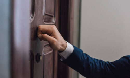 Cropped view of collector knocking on door with hand